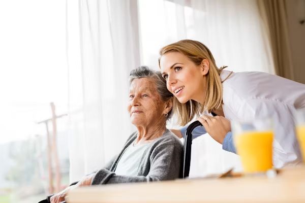 A carer and resident looking out of a sunny window together