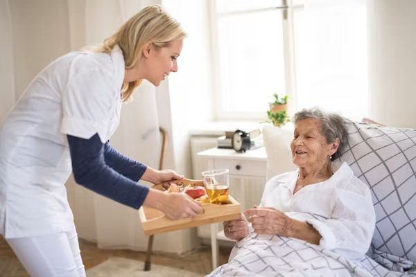 A carer bringing a tray to a resident in bed