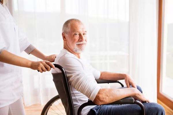 A carer helping a smiling resident in a wheelchair